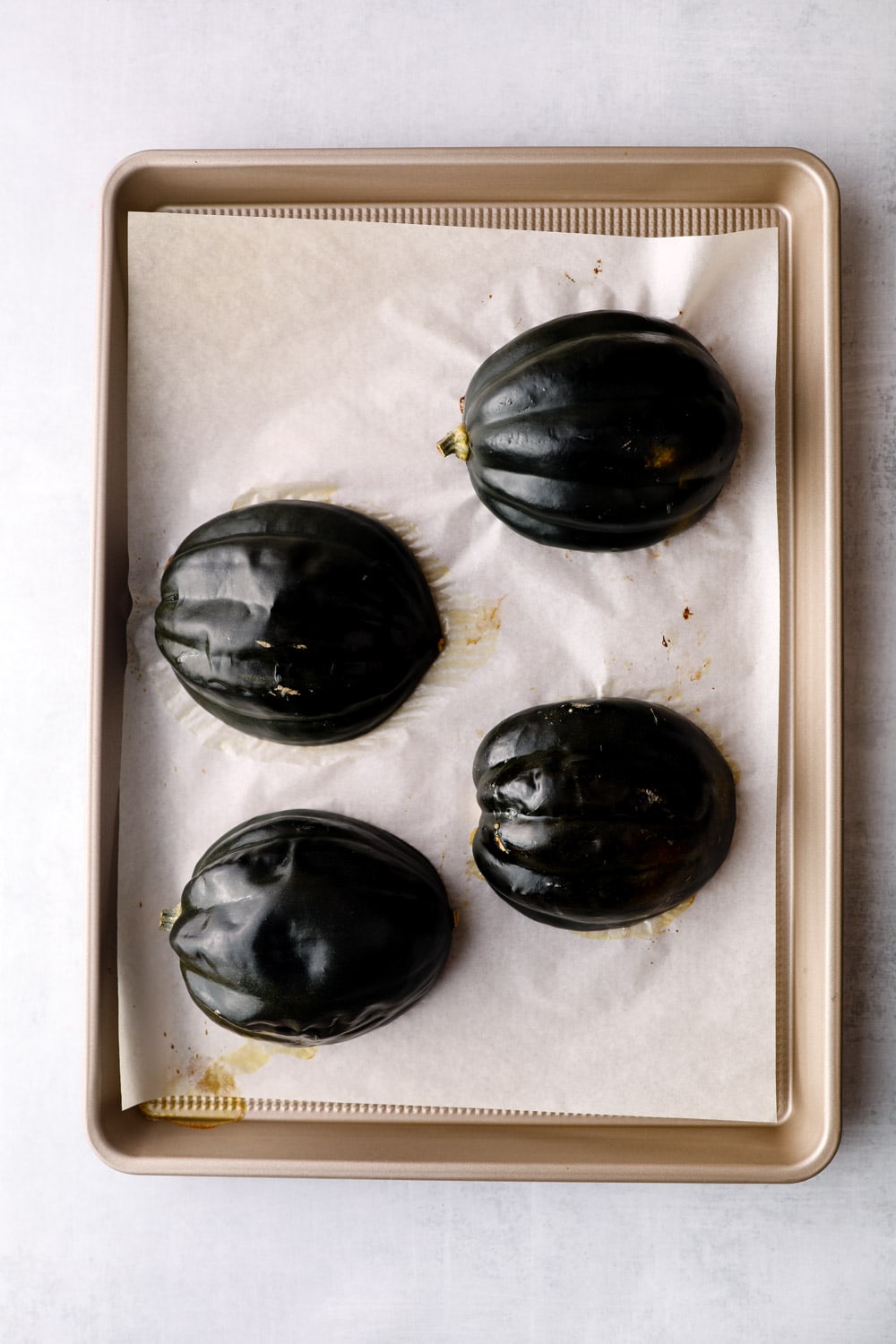 Acorn squash roasting on a sheet pan.