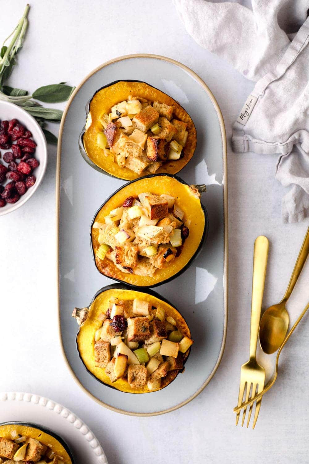 Stuffed Acorn Squash on a platter with cranberries, sage, and gluten free bread