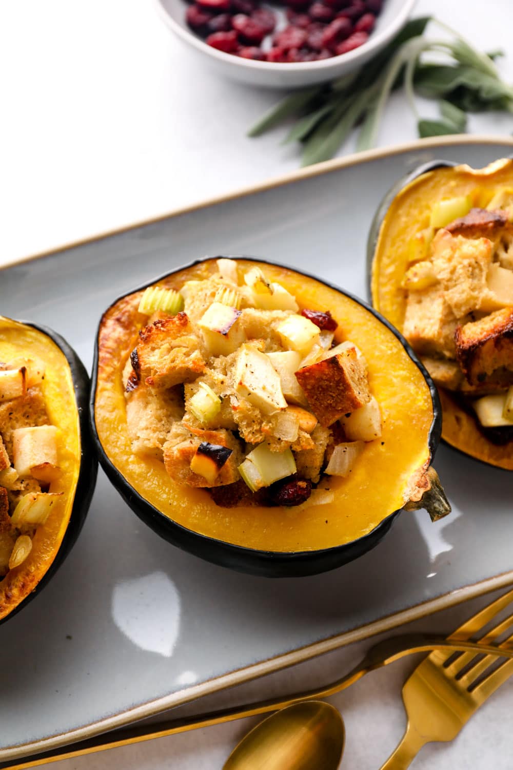 Stuffed Acorn Squash on a platter with cranberries and sage.