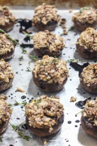 These Vegan Stuffed Mushrooms are a fast and easy party appetizer recipe with less than 10 ingredients! They are filled with nutty walnuts, salty olives, and fresh herbs and finished with a drizzle of sweet balsamic glaze. | CatchingSeeds.com