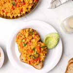 Two pieces of toast with chickpea scramble and avocado.