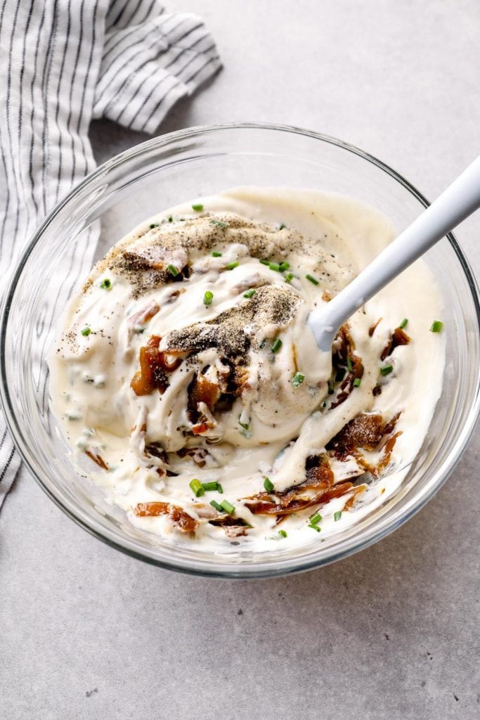 Vegan French Onion Dip being stirred in a mixing bowl.