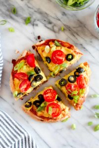 This Mexican Tortilla Pizza is double decker masterpiece filled with creamy beans, tempeh taco meat, and lots of cheese. A perfect healthy weeknight recipe. | CatchingSeeds.com