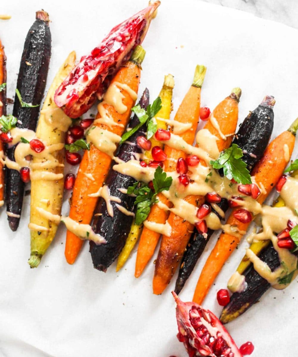 This 7 ingredient Whole Roasted Carrots with Maple Tahini recipe is easy to make but boasts BIG flavors. This light side dish is paleo and vegan! | CatchingSeeds.com