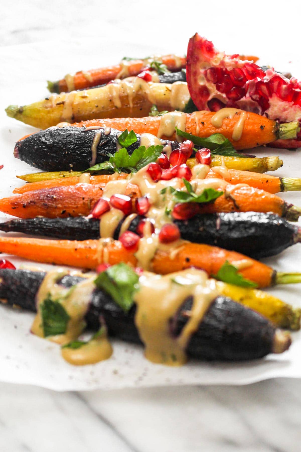 This 7 ingredient Whole Roasted Carrots with Maple Tahini recipe is easy to make but boasts BIG flavors. This light side dish is paleo and vegan! | CatchingSeeds.com