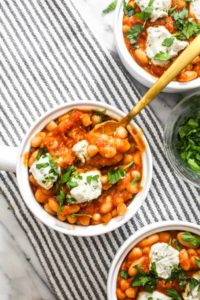Tomato Cannellini Cassoulet with a homemade tomato sauce is bursting with comforting flavors! The DIY sauce is balanced by using canned beans to make this 8 ingredient side recipe both easy and delicious. The dollops of dairy-free cheese on top add even more rich creamy flavor. | CatchingSeeds.com