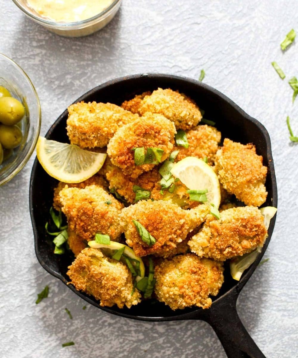 Gluten Free Baked Artichokes with Smoky Paprika Aioli are the perfect New Year's Eve appetizer. With its golden crispy crunch, you'd never believe this recipe is baked instead of fried! A special 3 step breading process is a foolproof way to ensure the coating adheres to the artichokes – and it also happens to be egg free and vegan! | CatchingSeeds.com