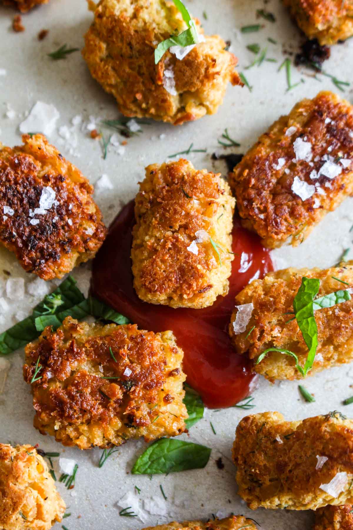 Mediterranean Chickpea Cauliflower Tots are a fun and healthy spin on traditional tots! This side dish gets golden brown and crispy on the outside and is melt in your mouth on the inside. Plus, this recipe sneaks in some extra veggies, is gluten free, and vegan! | CatchingSeeds.com