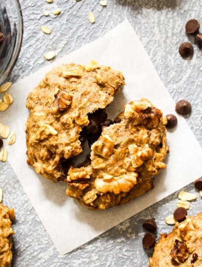 A Chocolate Stuffed Banana Nut Breakfast Cookie on a piece of parchment paper wth chocolate chips, oats, and walnuts.