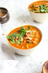 Two bowls of African peanut stew topped with cilantro and peanuts.
