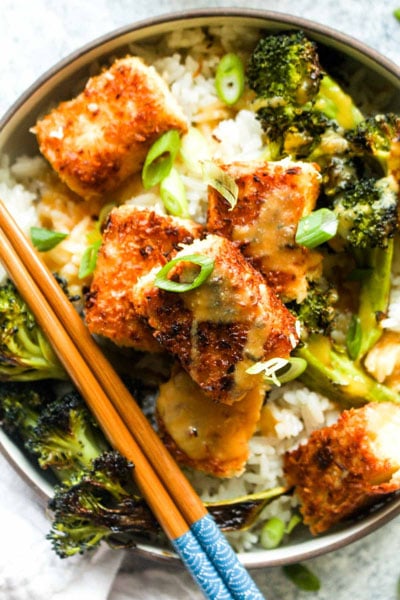Coconut Crusted Tofu over a bed of ginger coconut rice and roasted broccoli with habanero pineapple sauce in a bowl.