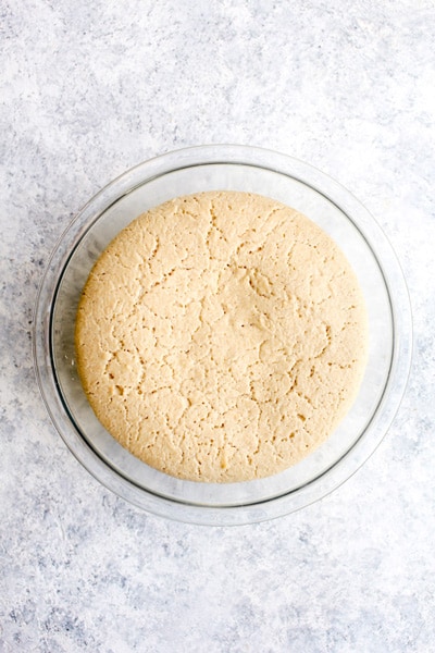 A bowl of puffy gluten free pizza crust dough after it has risen for one hour.