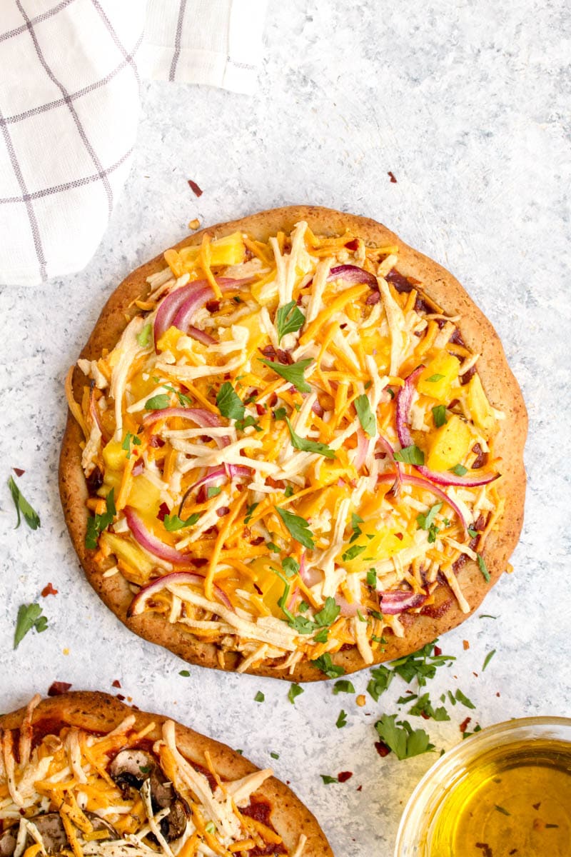 A gluten free pizza crust topped with sauce, cheese, pineapple, and onions baked to perfection.