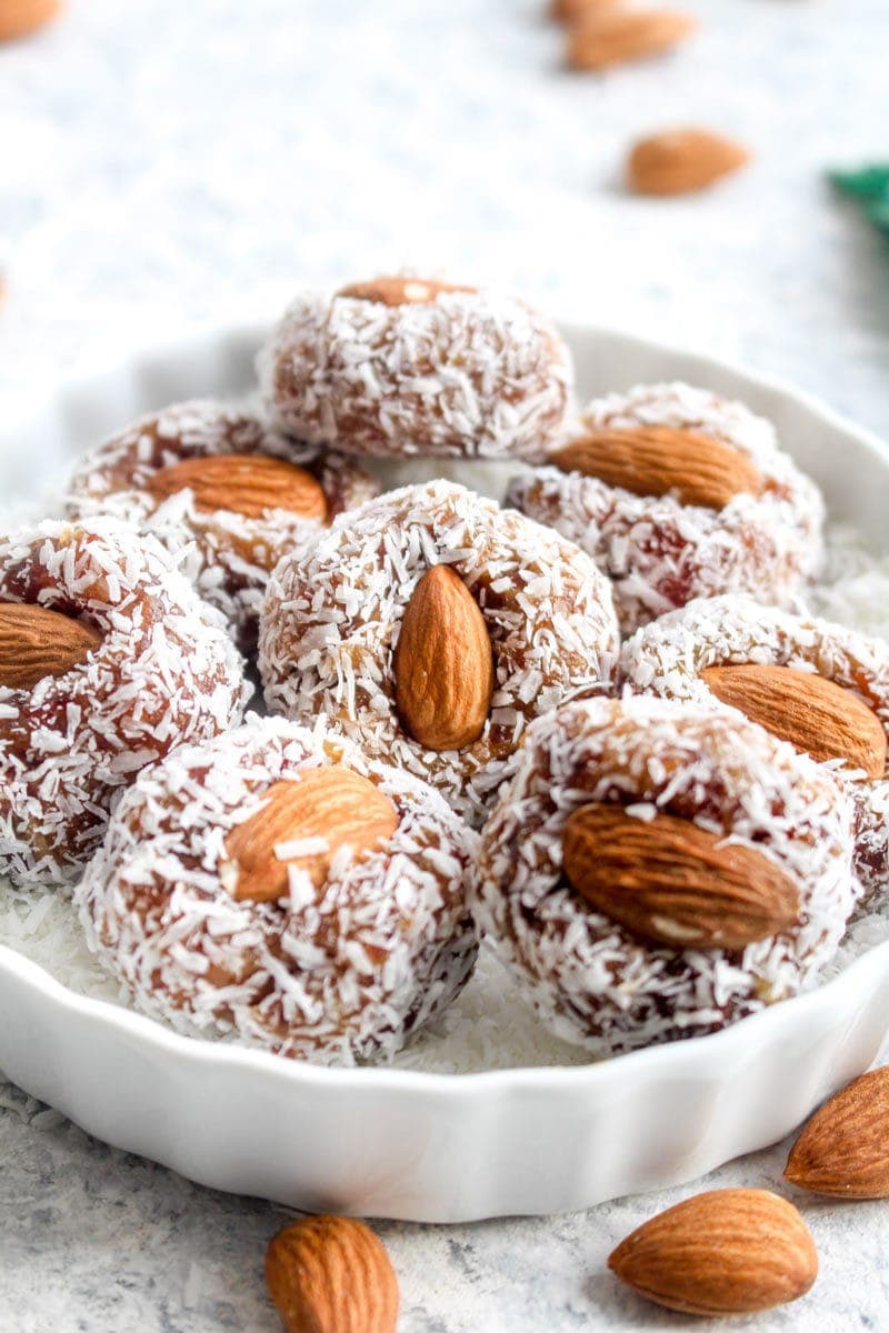 A white dish full of date coconut rolls.