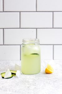 Cucumber real fruit sparkling water in a mason jar with a slice of lemon and cucumber.