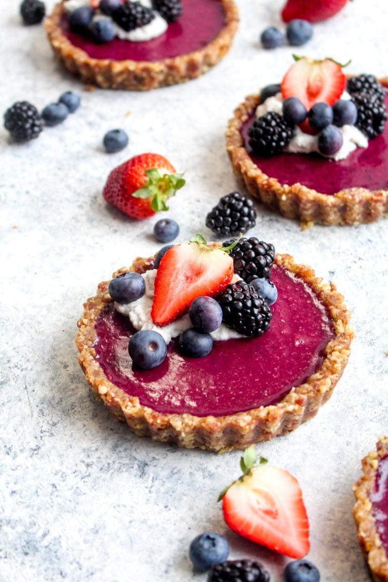 A no bake triple berry tart topped with coconut cream and berries.