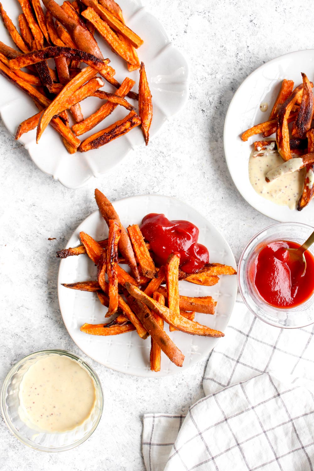 Seasoned sweet potato fries on a white plate with ketchup.