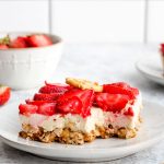Healthy pretzel salad with a bite out of it topped with strawberries.