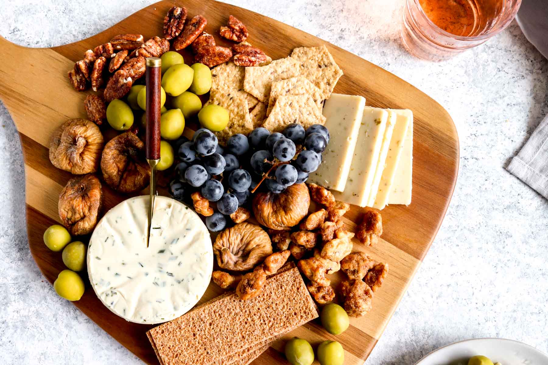 A Vegetarian charcuterie board with grapes, nuts, olives and cheese.