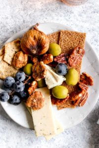 A plate filled with cheese, nuts, and fruit from a vegetarian charcuterie board.