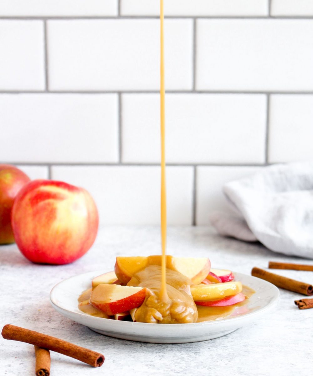 Healthy tahini caramel being poured over apple slices.