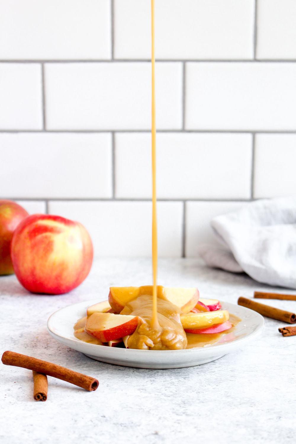 Healthy tahini caramel being poured over apple slices.