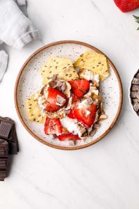 Dessert Seven Layer Dip and crackers on a plate with chocolate and strawberries.