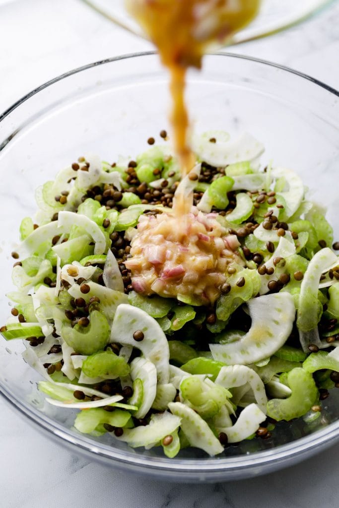 Dressing being drizzled over lentil salad.