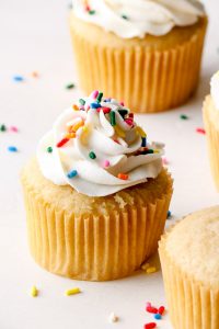 Vegan vanilla buttercream with sprinkles on a vanilla cupcake.