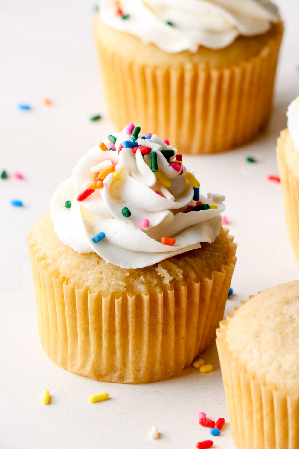 Vegan vanilla buttercream with sprinkles on a vanilla cupcake.