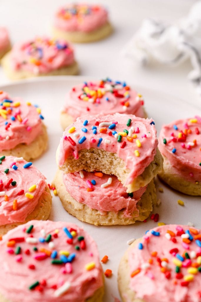 Stacked sugar cookies on a plate with frosting.