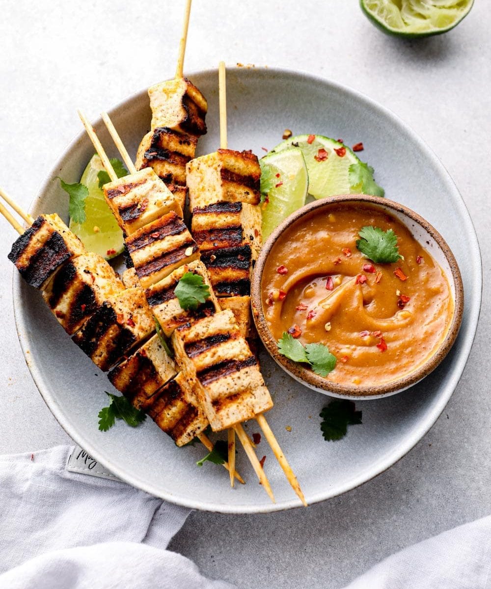 A plate of tofu satay skewers and peanut sauce.