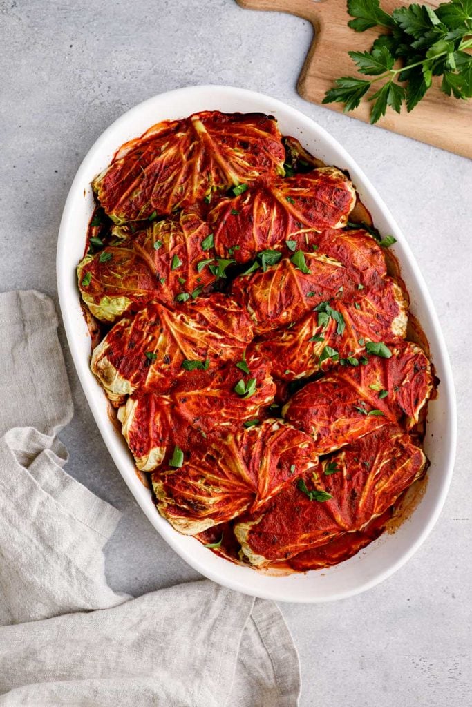 Baked vegetarian cabbage rolls in a white baking dish.