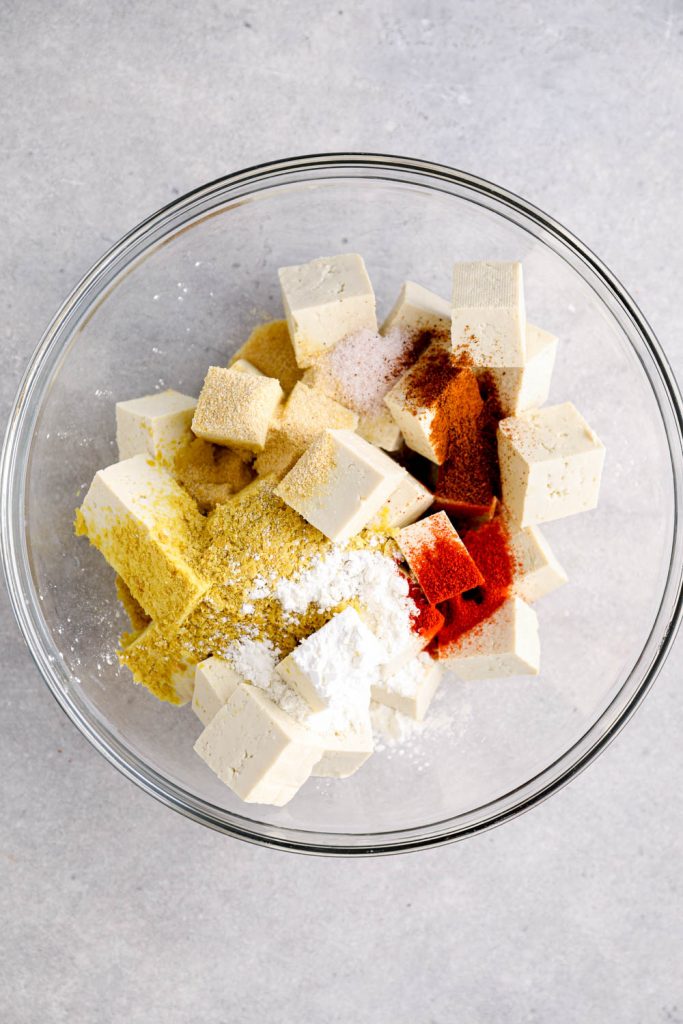 A bowl with tofu and seasonings.