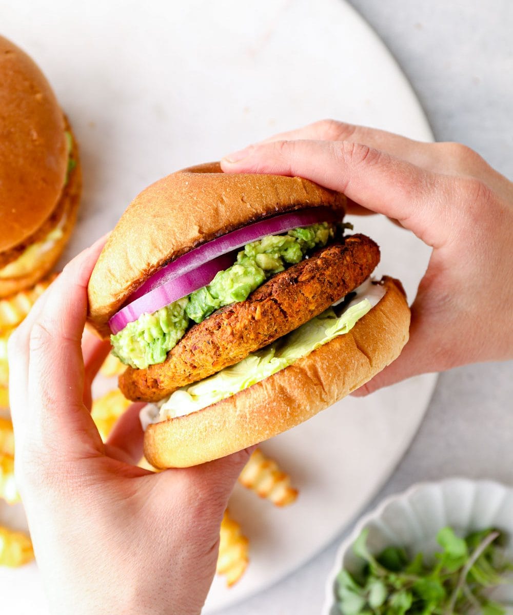 A chickpea burger held between two hands.