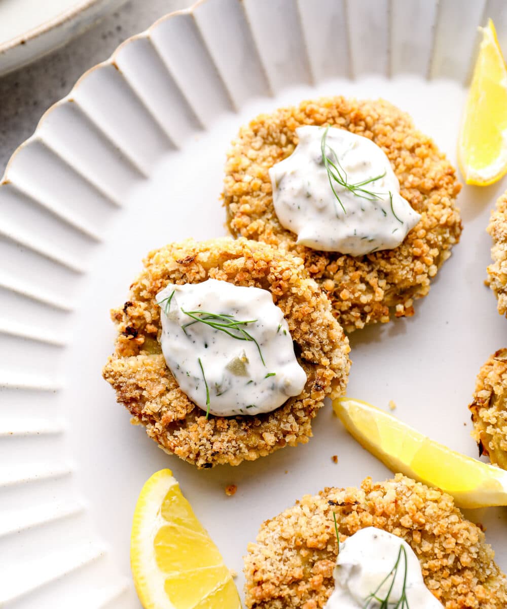 Vegan crab cakes with lemon wedges on a white plate.