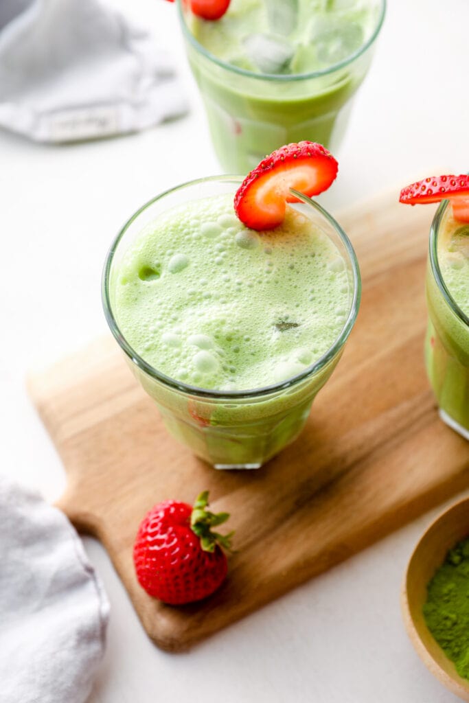 Three strawberry matcha lattes in glasses with ice.