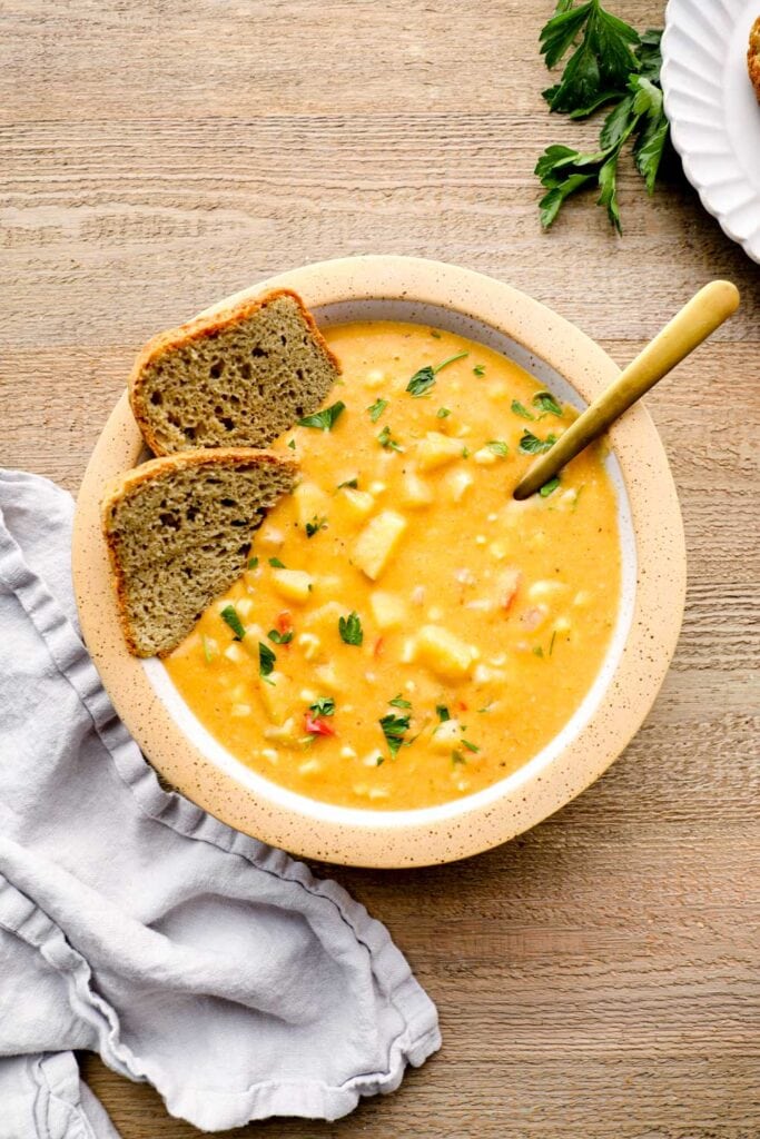 Bread dunking in vegan corn chowder.
