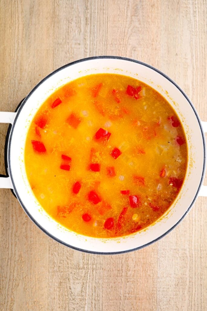 Onions, bell pepper, and broth in a soup pot.