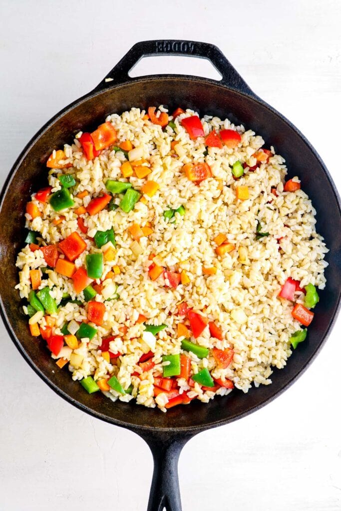 Rice and veggies cooking in a skillet.