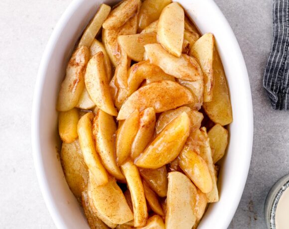 Baked cinnamon apples in a white baking dish.