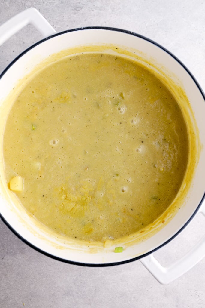 Vegan potato soup simmering in a white dutch oven.