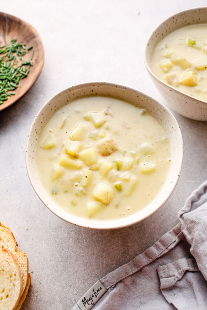 A bowl of vegan potato soup on a grey background.