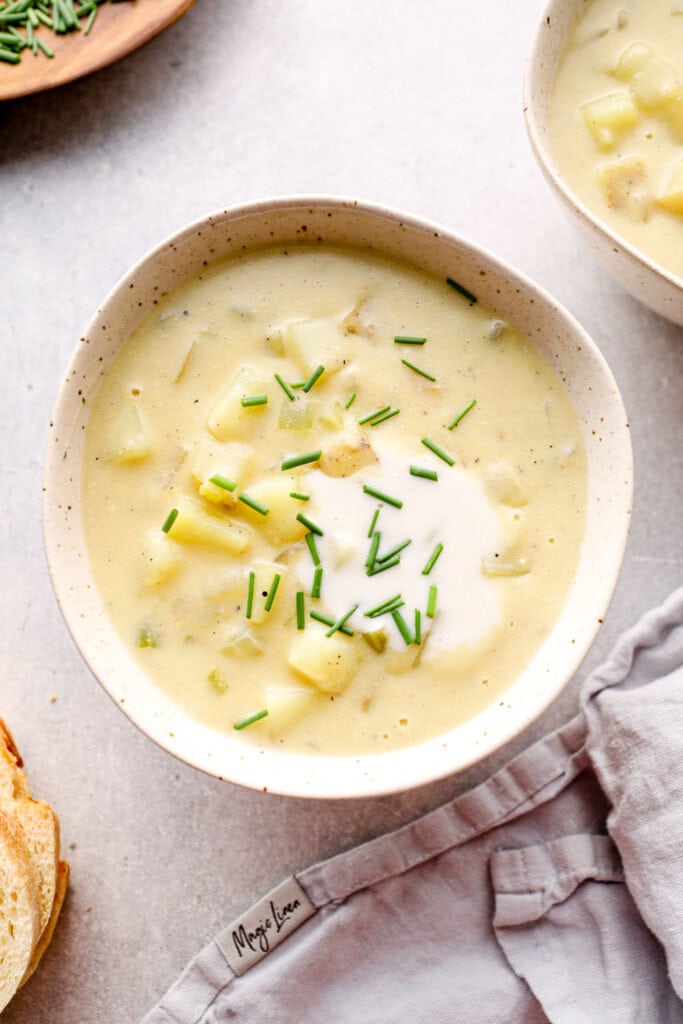 A bowl of vegan potato soup with sour cream and chives.