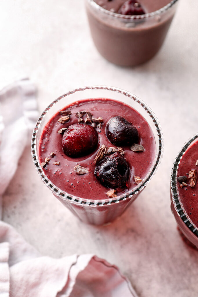 Chocolate cherry smoothies topped with cherries and cacao nibs.