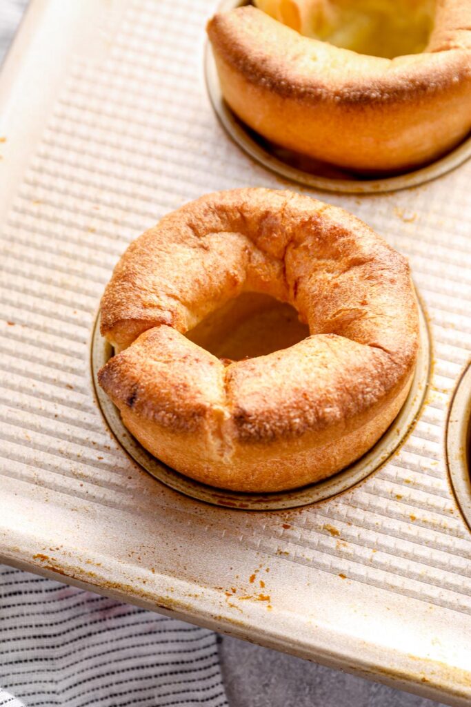 A golden puffed gluten free yorkshire pudding in the muffin tin.