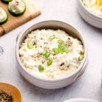A bowl of vegan cottage cheese topped with black pepper and green onions.