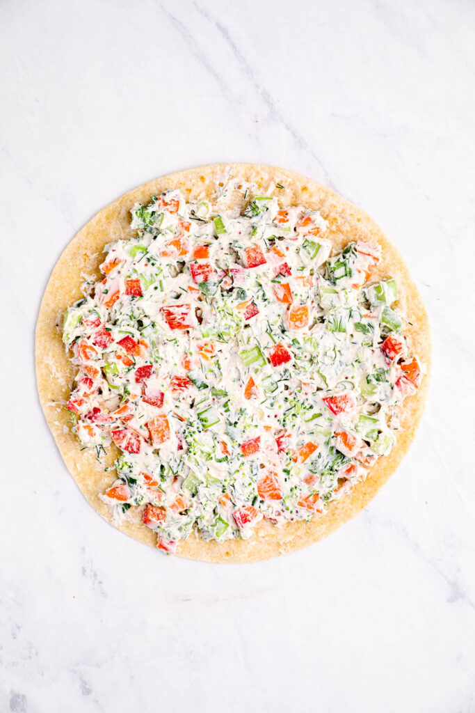 The vegan cream cheese and vegetable mixture spread out onto a tortilla.